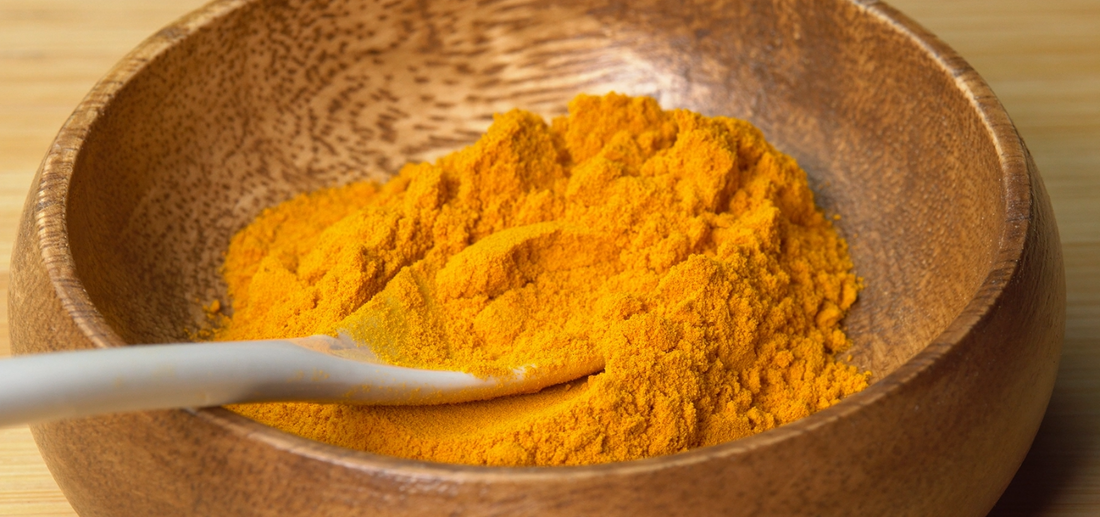 turmeric powder spice in wooden bowl with spoon
